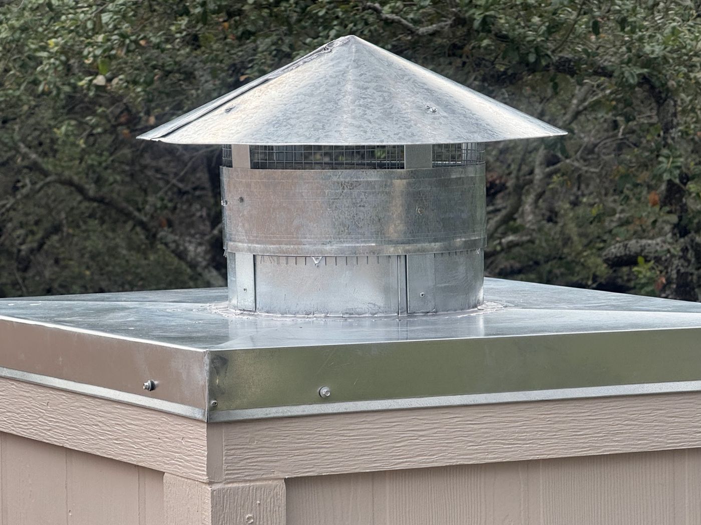 Custom galvanized steel chimney cap with mesh screen on a tan chimney, San Antonio