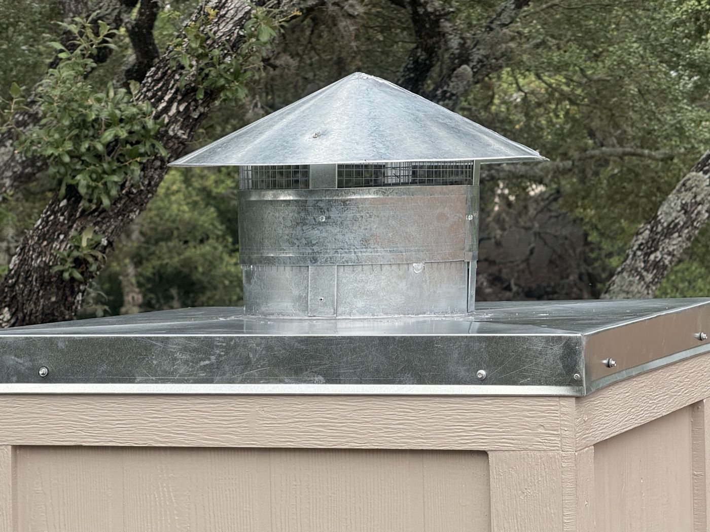 Galvanized chimney cap with protective mesh on a painted chimney chase, San Antonio