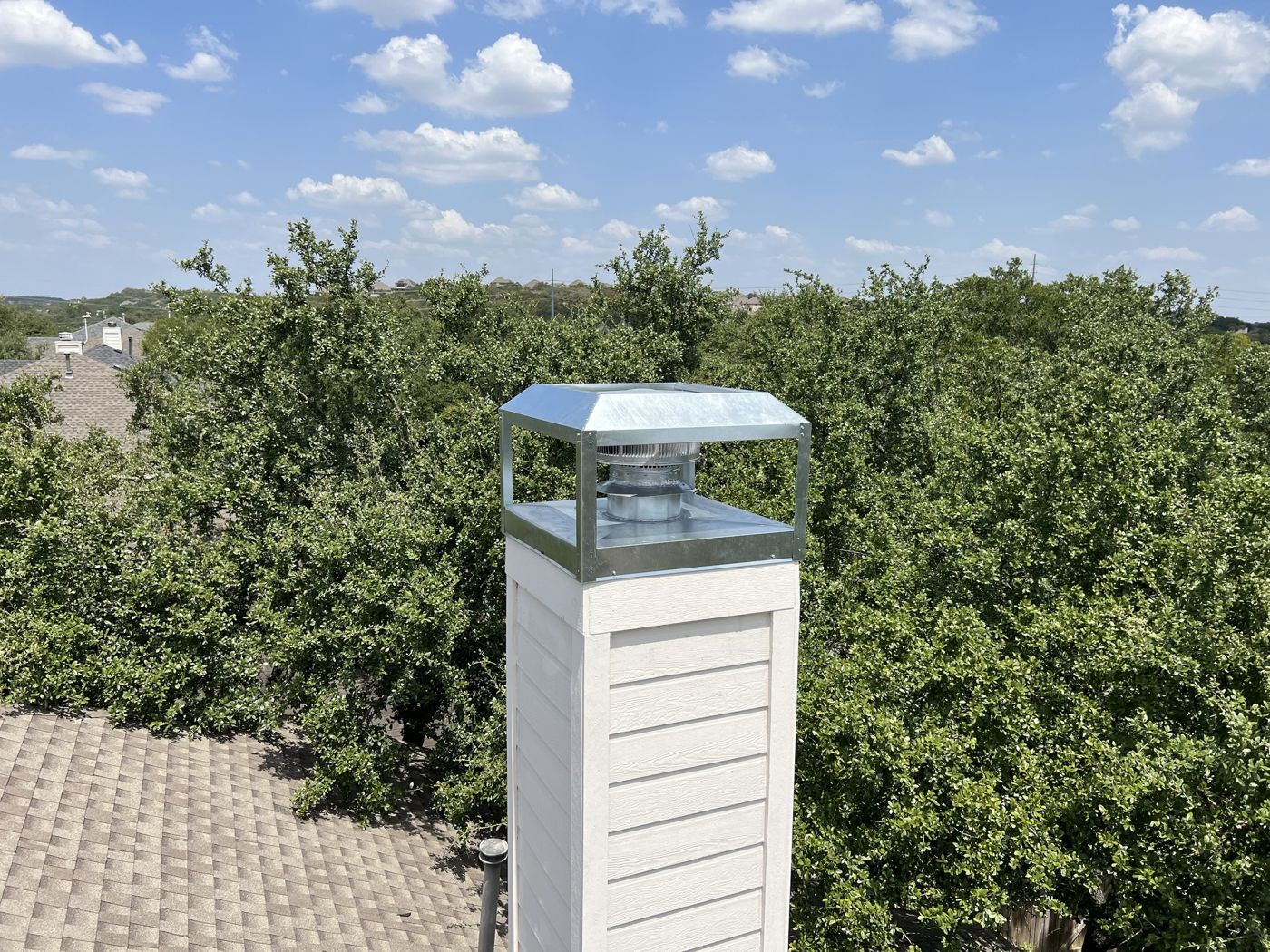 Custom galvanized chimney cap with four posts on a white chimney chase